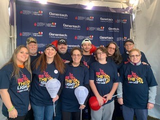 group of 10 white people various ages wearing Light The Night tshirts two holding white balloons three holding red balloons