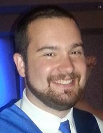 young white man with brown hair beard mustache wearing a white shirt with a blue tie and vest