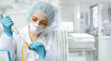 A scientist injects a liquid substance into a vial. 