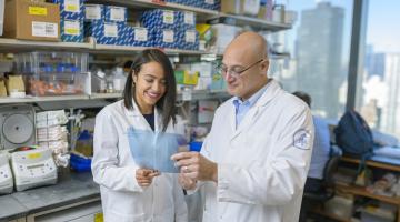 (Dr. Salima Benbarche (left) and Dr. Omar Abdel-Wahab (right) look at a paper in their lab at Memorial Sloan Kettering Cancer Center in New York City.