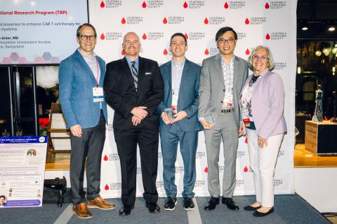 Five individuals pose for a photo in front of a Leukemia & Lymphoma Society backdrop