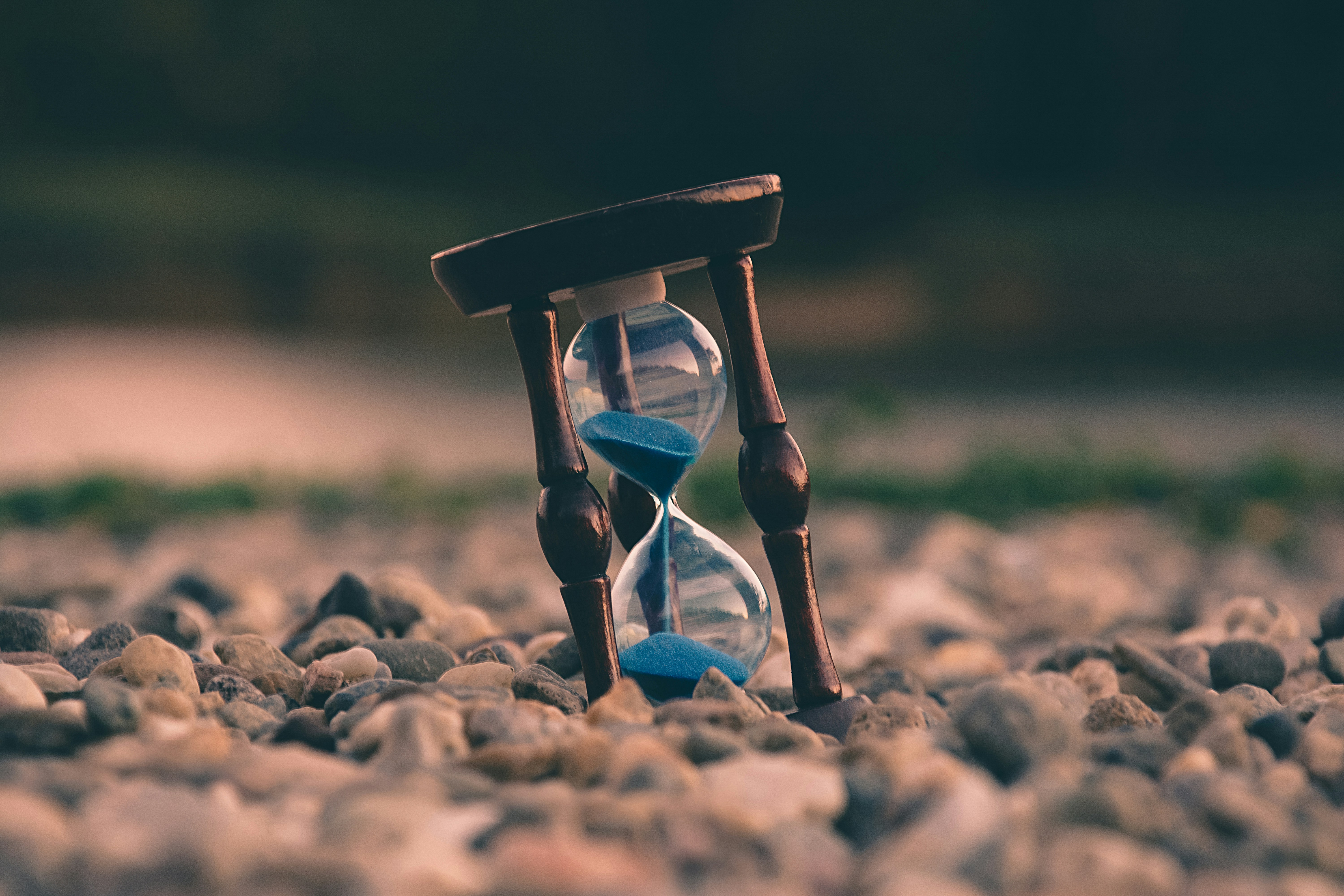 Hourglass with sand, sitting on rocks, blurry background