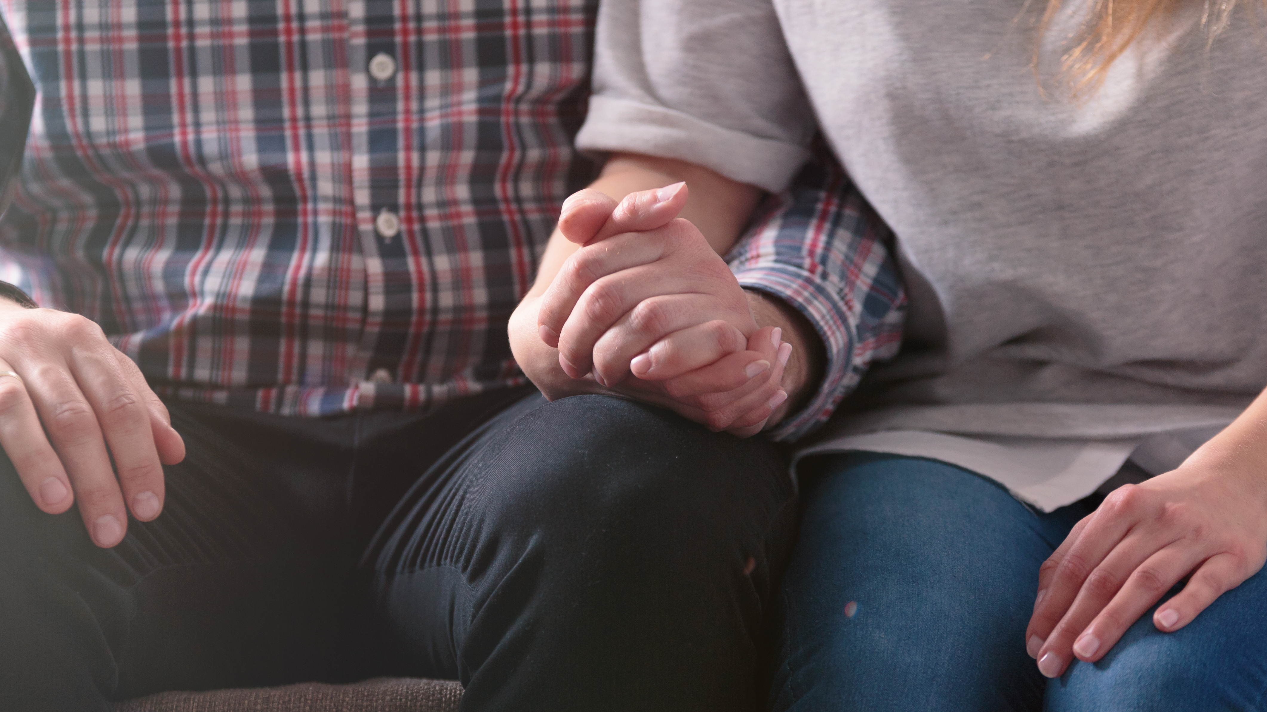 close up, two people holding hands, sitting on a couch