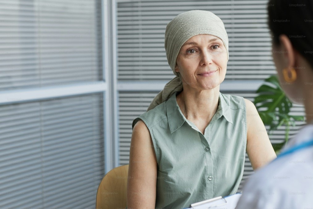 A woman with a bandana sits across from another person behind a desk