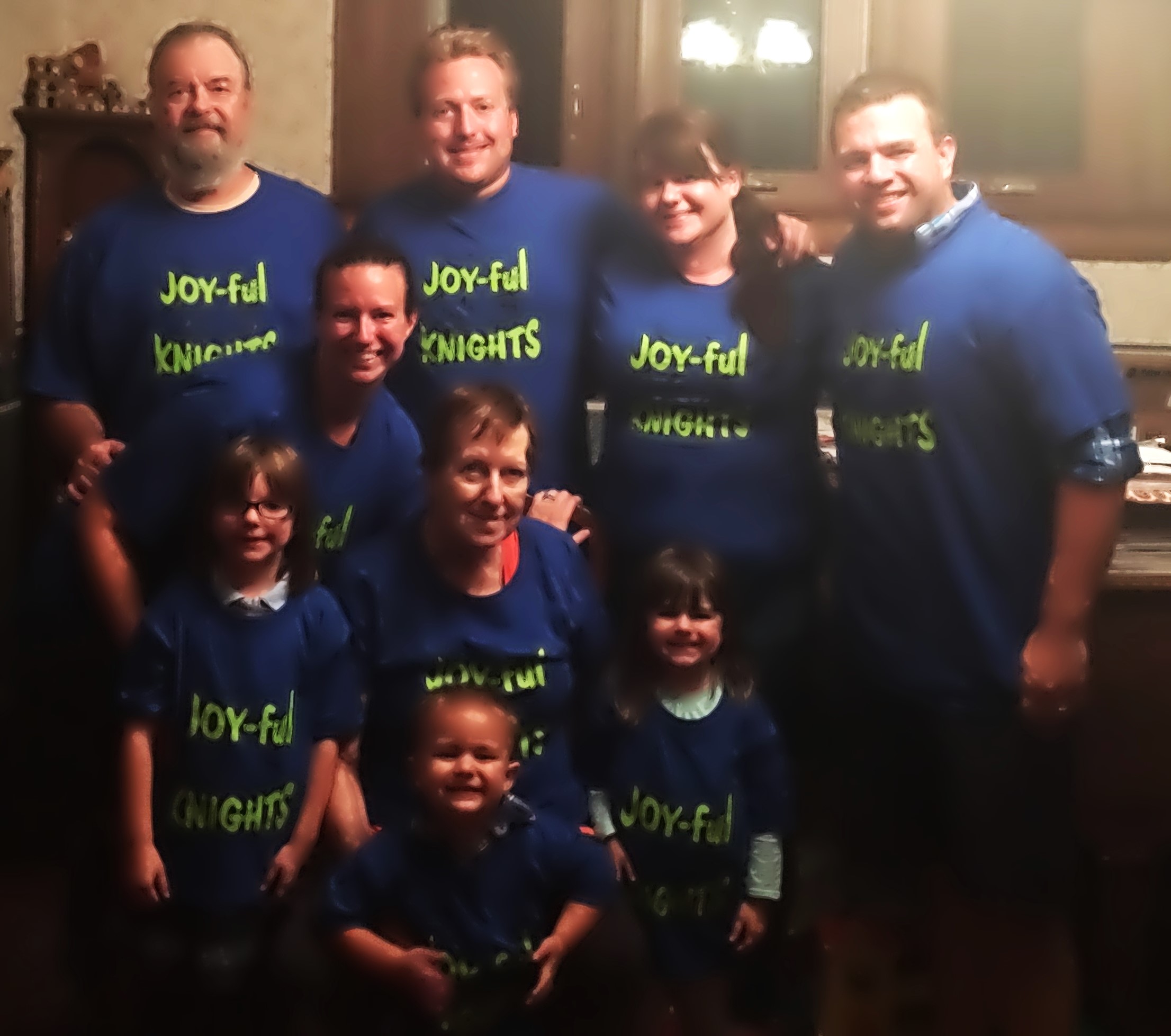 Six adults and three children all wearing blue shirts that say Joy-ful Nights