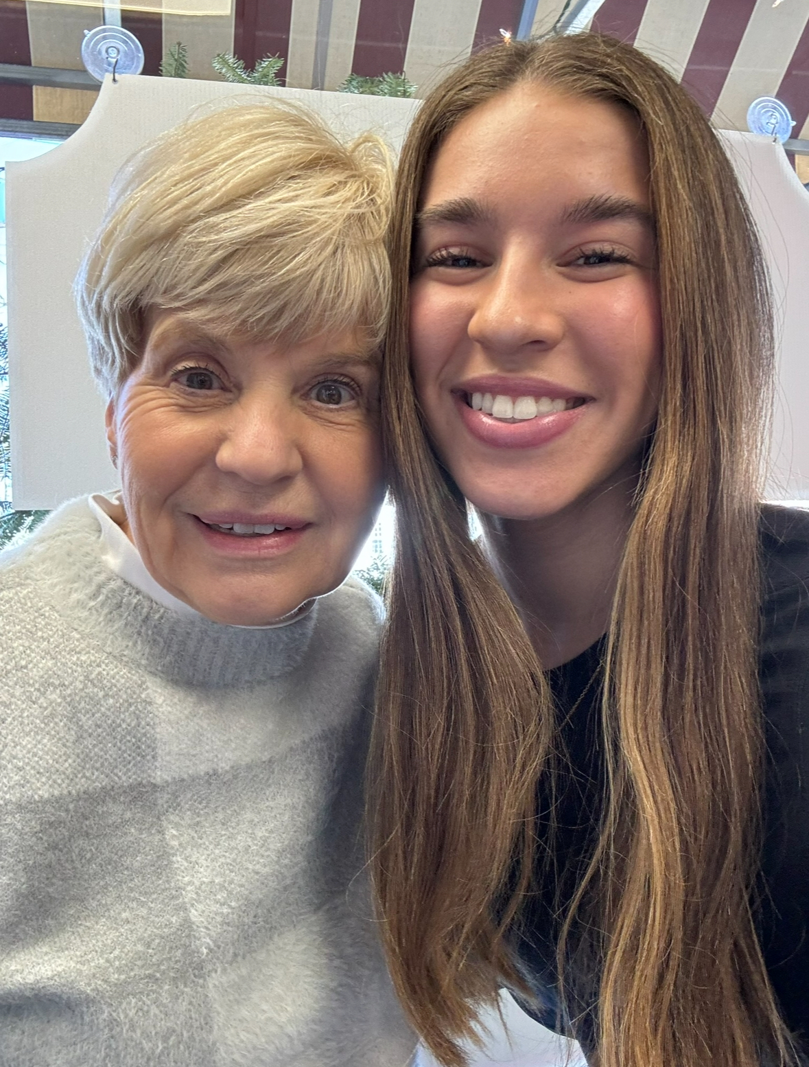 older woman with short blond hair in a sweater next to younger woman with long brown hair and a black shirt