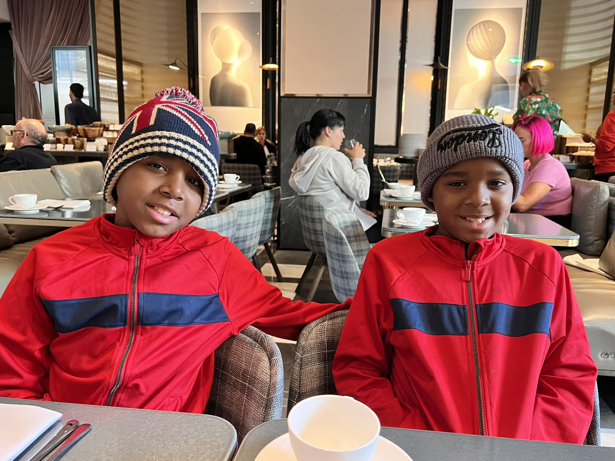 two young black boys wearing knitted hats and matching red and blue jackets