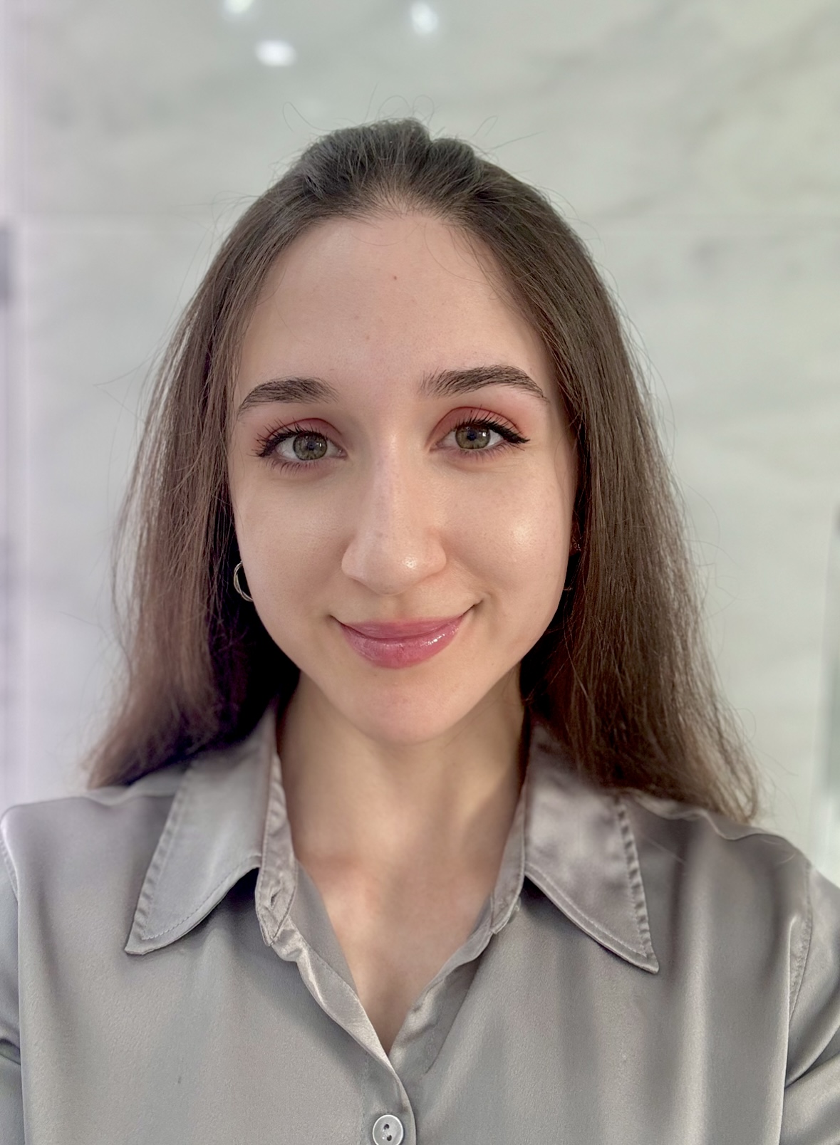 young hispanic woman with large green eyes an pink lipstick wearing a grayish blouse