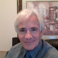 James older white man with white hair wearing a shirt and tie sitting in front of framed artwork