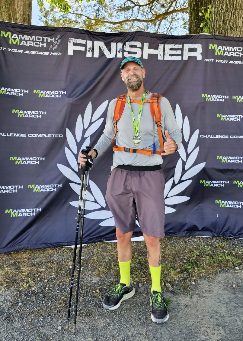 Athletic blood cancer survivor standing with finisher and baseball cap