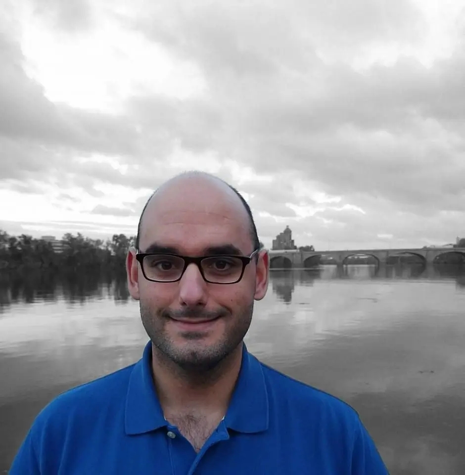 Acute myeloid leukemia survivor wearing a blue buttoned shirt in front of a beautiful landscape