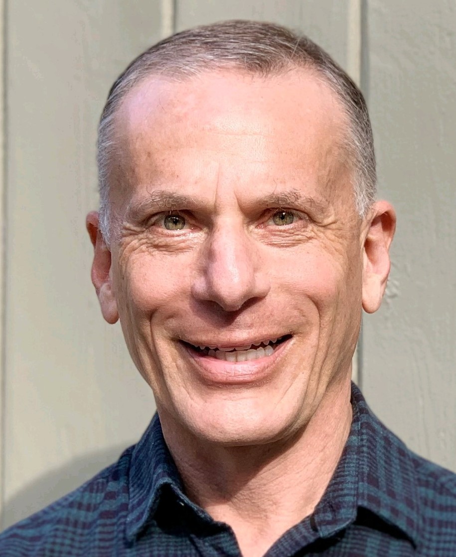 Geoff older white man with graying hair smiling and wearing a blue checked shirt