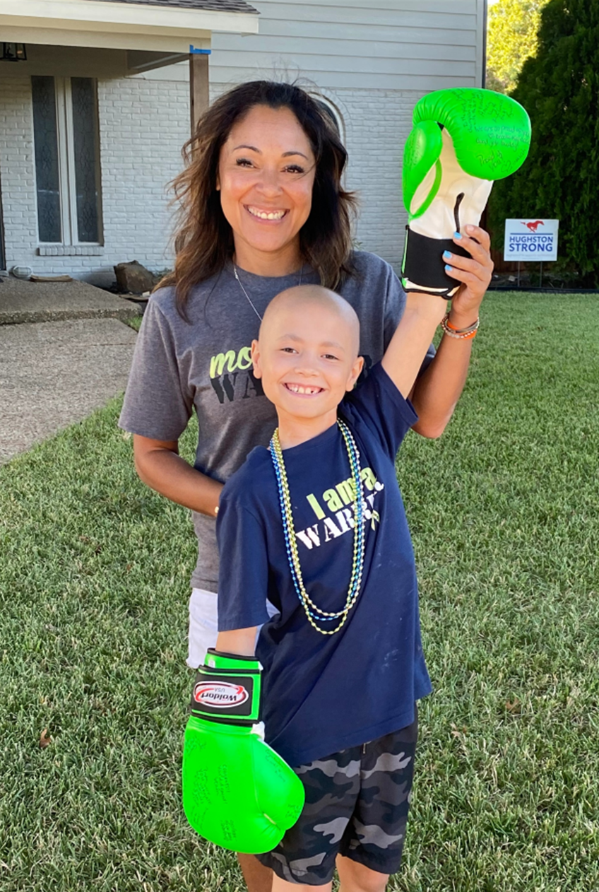 Peyton young hispanic mom in a gray tshirt with her bald son wearing bright green boxing gloves and an I Am a Warrior tshirt