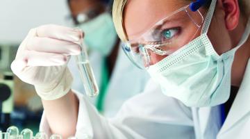 A researcher analyzes a specimen in a test tube.