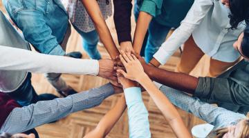 Group of people putting hands in center