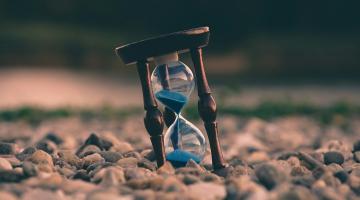 Hourglass with sand, sitting on rocks, blurry background