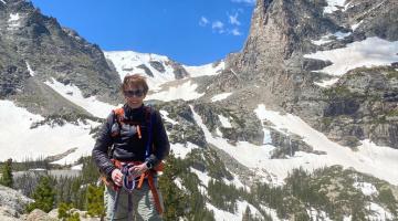 Alice, myeloma survivor, on a hiking trip, standing in front of mountains