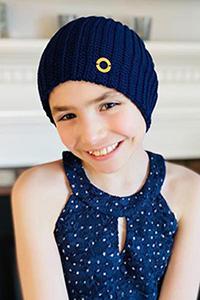 Ava, smiling at the camera, wearing a blue hat and shirt