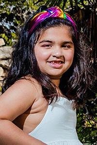 Kenza, smiling at the camera, wearing a colorful headband