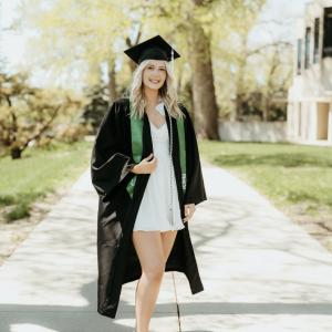 Young blond woman in a cap and gown, green stole and platform shoes