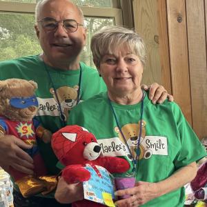 Older man with leukemia with his wife in green bear t-shirts holding stuffed bears