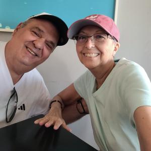 older white couple he has on a ball cap and white t-shirt and she has on pink ball cap and glasses and a white t-shirt