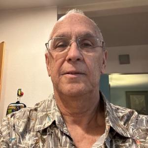 older white man with glasses and balding wearing a grayish patterned shirt