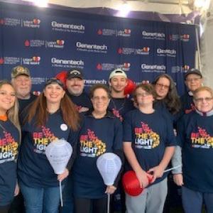 group of 10 white people various ages wearing Light The Night tshirts two holding white balloons three holding red balloons