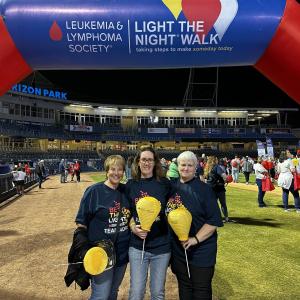 three white women holding gold balloons middle one with glasses all wearing LTN tshirts