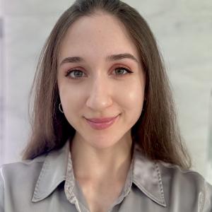young hispanic woman with large green eyes an pink lipstick wearing a grayish blouse
