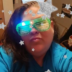 youngish native american woman wearing green sparkly glasses and a blue shirts with stars and a LTN balloon