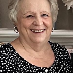older white woman with short white hair wearing silver hoop earrings and a black and white polka dot blouse