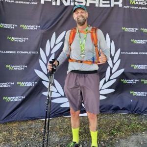 Athletic blood cancer survivor standing with finisher and baseball cap