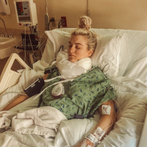 Brescia young white woman laying in a hospital bed with blond hair pulled into a pony tail on top of her head eyes closed wearing green leaf hospital gown