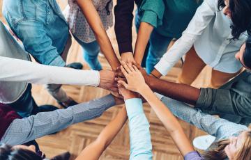 Group of people putting hands in center