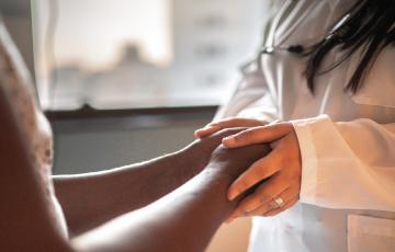 Doctor in white coat holding a patient's hands