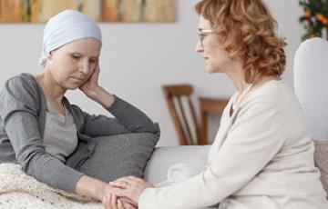 Patient sitting with friend or family member, holding hands. It looks like a tense, difficult moment.