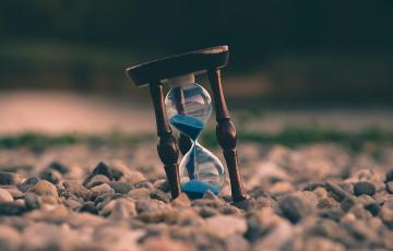 Hourglass with sand, sitting on rocks, blurry background