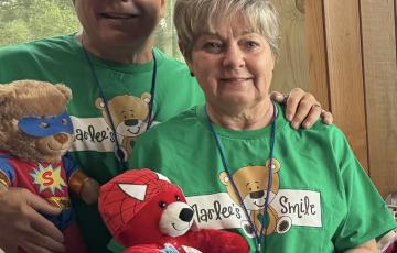 Older man with leukemia with his wife in green bear t-shirts holding stuffed bears