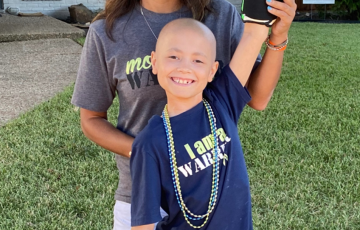 Peyton young hispanic mom in a gray tshirt with her bald son wearing bright green boxing gloves and an I Am a Warrior tshirt
